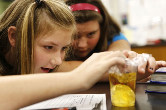 Sixth-grade students Emmy Greene and Kayarin Montgomery watch their experiment that simulates how a cell membrane works during Lisa Elam's science class. The plastic bag was filled with corn starch and placed in an iodine dilution. Photo by Amy Wallot, Sept. 10, 2012