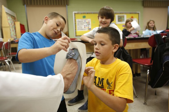 Fourth-grade students Gavin Whitt and Josh Fraley get a rubbing of principal Vanessa Maggard's shoe during Michelle Ison's art class. It was Gavin's idea to ask her to participate.  Photo by Amy Wallot, Sept. 10, 2012