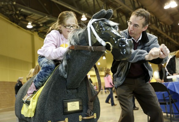 Remi Bellocq, executive director of equine programming at Bluegrass Community and Technical College, gives Stanton Elementary School (Powell County) kindergarten student Kelsey Howell some riding tips during the Kentucky Equine Youth Festival at the Kentucky Horse Park. Photo by Amy Wallot, March 27, 2013