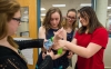 Hailey Poe, left, and Lauren Freeman, right, secure a device onto the arm of fellow Women’s Engineering Academy student Hannah Sipple as Janie Pierce looks on. The device helps secure an iPhone to the user’s wrist. Photo by Bobby Ellis, April 7, 2016