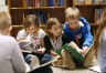 After checking out books, students find spots on the floor and read together.  Photo by Amy Wallot, Dec. 2, 2014
