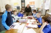 Fifth-grade teacher Josh Feldmann clarifies information about the Plymouth Colony a group of students at Johnson Elementary School (Ft. Thomas Independent). They were creating a commercial encouraging settlers to choose their colony. Photo by Amy Wallot, Oct. 21, 2014