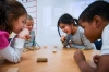 Shaina Stone, a 1st-grade student at Lowe Elementary School, and her classmates use straws to attempt to move rocks across a table as they experimented with the effects of wind on different objects. Students talked about their conclusions with a Kentucky Science Center education staff member via video conference. Photo by Bobby Ellis, March 14, 2017