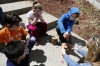 Third-grade students watch as Traci Tackett helps 2nd-grade student Luke McName drill holes in a small log to create a mason bee house for the students' garden. Photo by Amy Wallot, April 28, 2015​