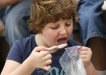 Fourth-grade student Sarah Henderson eats homemade chocolate ice cream she made in the Mobile Science Activity Center at Tollesboro Elementary School (Lewis County). The ice cream was “Good!” she said. Photo by Amy Wallot; May 24, 2011