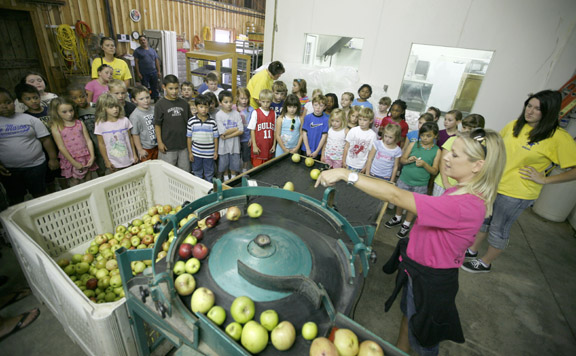Evan's Orchard employee Leigh Ayres demonstrates the apple sorter for students from Anne Mason Elementary School (Scott County) Sept. 22, 2010. Photo by Amy Wallot