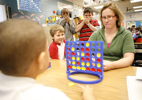 Teacher Amy Pavona plays Connect Four with 4th-grade student D'Onta Lane during an indoor recess at Dixie Elementary Magnet School (Fayette County) Jan. 6, 2011. Looking on, Brennan Aulds, left, Kendrick Curry, center, and Drew Hensley realize D'Onta is going to win the game. Photo by Amy Wallot