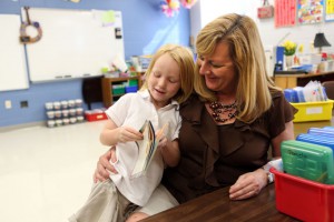 Kindergarten teacher Amy Wood hugs student Karina Turner as they look through a book at West Point Elementary School (West Point Independent). Wood, the only kindergarten teacher at the school, and her assistant attended the training for the screener. Photo by Amy Wallot, Aug. 15, 2012