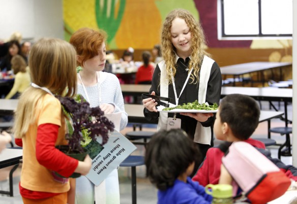 Student Energy Team members Mikayla Elverson, Madison Woods and Natalie Fowler pass out samples of kale chips during lunch at Rosa Parks Elementary School (Fayette County). Team members also shared information about the kale plant and informed students the kale was grown in Bourbon County as part of the Farm to School program. Photo by Amy Wallot, Jan. 17, 2013