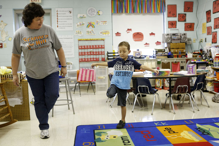 Caleb Leach stands on one foot with his eyes closed for paraprofessional Cathy Reynolds as a demonstration of his gross motor skills for the kindergarten screener at Science Hill Elementary School (Science Hill Independent). Photo by Amy Wallot, July 30, 2013