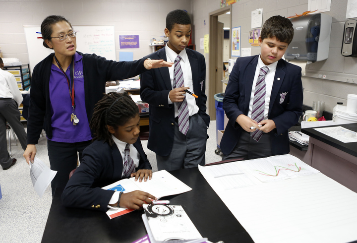 Kentucky Middle School Teacher of the Year Melanie Trowel helps Micah Lowe, Jayden Lydian and Anthony Wright with a graph analyzing daylight length and the angle of the sun during her 8th-grade science class at Carter G. Woodson Academy (Fayette County). Photo by Amy Wallot, Nov. 6, 2013