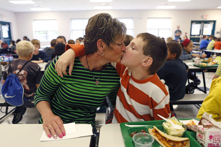 Barbara Westphal gives a kiss to her grandson 3rd-grade student Dyelan Westphal during lunch. She chatted with him and his friends during the meal. Photo by Amy Wallot, Oct. 28, 2013