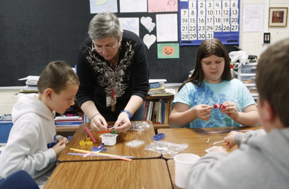 Art teacher Dorothea Broughton helps 5th-grade student Hunter Ross assemble his paper strips during a quelling project at Kit Carson Elementary School (Madison County). At right, Haley Balen works on her ornament. Photo by Amy Wallot, Dec. 9, 2014