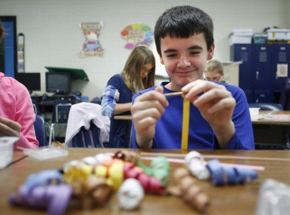Fifth-grade student Tom Morrison uses a wood dowel to wind paper strips during Dorothea Broughton's art class at Kit Carson Elementary School (Madison County). Morrison combined the brightly colored collection of swirls to make a firecracker-like ornament. Photo by Amy Wallot, Dec. 9, 2014