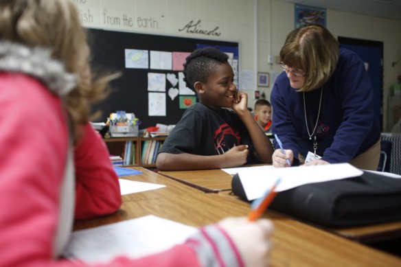 Rhonda Orttenburger helps 5th-grade student Cedric Reinhardt fill out a bracket to narrow down his favorite song during class at Kit Carson Elementary School (Madison County). After choosing a favorite song, the students were then writing an opinion piece on it. Photo by Amy Wallot, Dec. 9, 2014