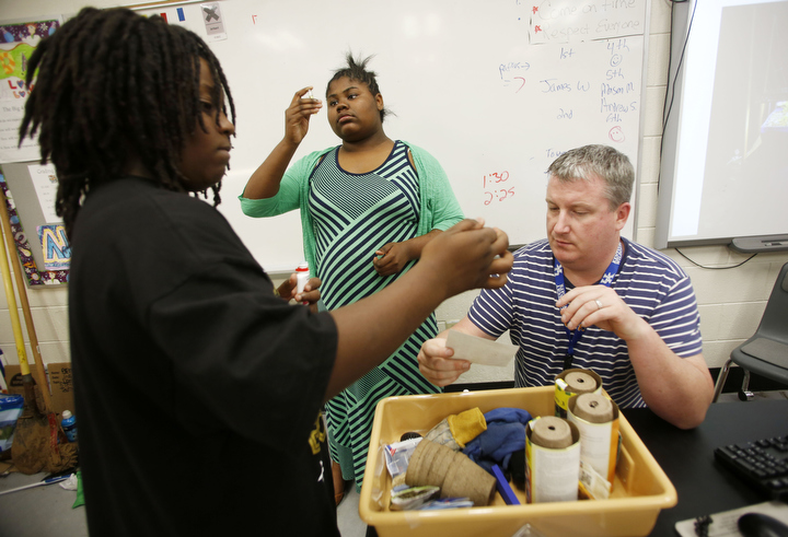 Science teacher Thomas Reed helps 6th-grade students Jamez Brooks and Antyana Cowan determine the pH levels of the tilapia tank as part of the aquaponics system at Bryan Station Middle School (Fayette County). Photo by Amy Wallot, May 8, 2015