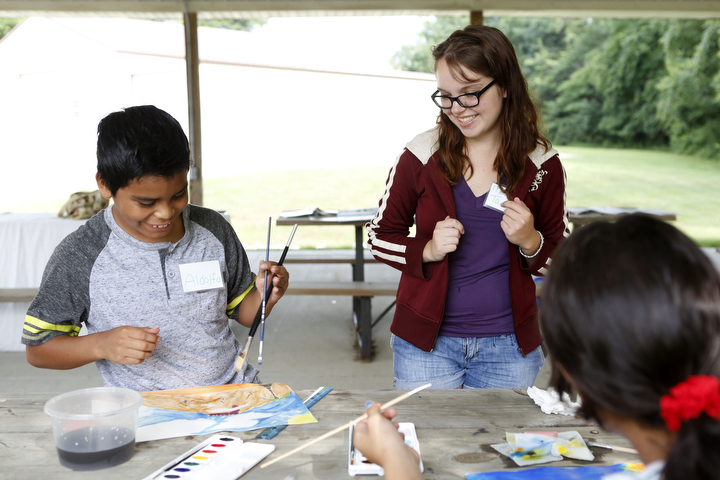 Eastern Kentucky University graduate Tamara Hounshell helps students with their paintings of the ocean during the Go With The Flow migrant writing summer camp. She plans on teaching after earning her Master's degree in ESL and Spanish. Photo by Amy Wallot, June 23, 2015