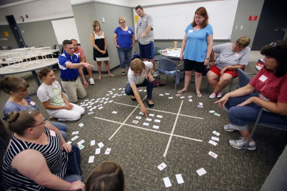 With the help of Northern Kentucky University assistant professor Aimee Krug, center, teachers create a giant board with the card game Set during the Math Teachers' Circle at Northern Kentucky University. Photo by Amy Wallot, July 20, 2015