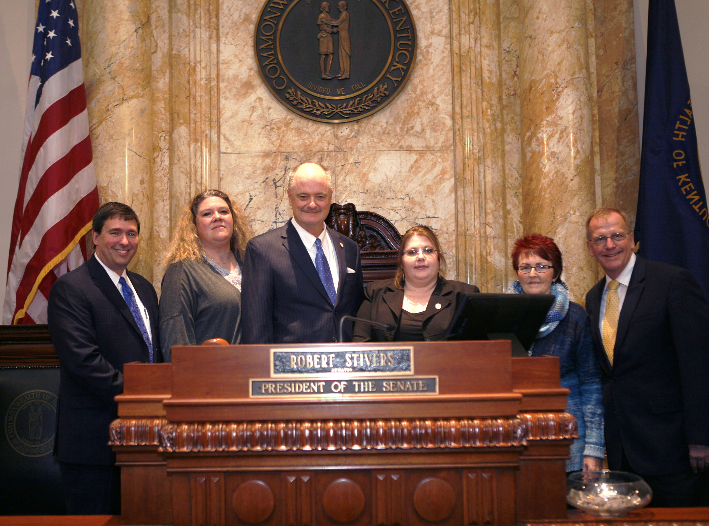 Sen. John Schickel (R-Union) stands with Kentucky Education Commissioner Stephen Pruitt and representatives from the Boone County School District at the rostrum of the Senate chamber at the Kentucky State Capitol prior to the reading of a resolution honoring the state’s school bus drivers. From left to right are Pruitt; Beverly Daniels, a bus driver for the Boone County schools; Schickel; Heather Roth, Boone County director of transportation; Helen Cottongim, Boone County transportation training coordinator; and Randy Poe, Boone County superintendent. The resolution was adopted unanimously by the Senate. Photo by Mike Marsee, Jan. 12, 2016