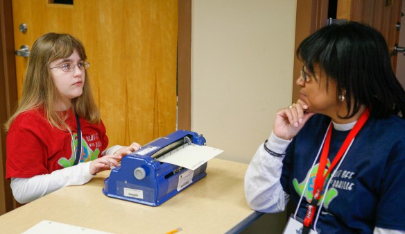 Karleigh Bruner uses a Braille typewriter to record an answer while a volunteer looks on during a reading comprehension test. Photo by Mike Marsee, Feb. 18, 2016
