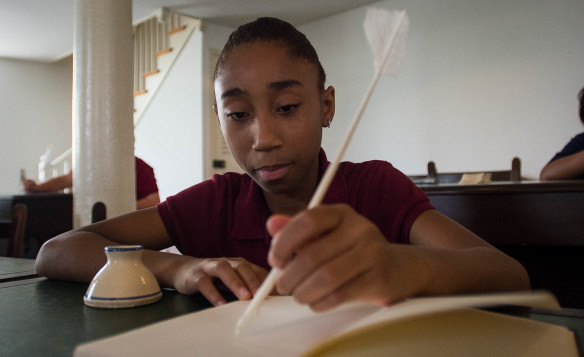 Jayden Lawless pretends to write with a quill during the tour of the House chamber in the Old Capitol building in Frankfort. Photo by Bobby Ellis, April 19, 2016