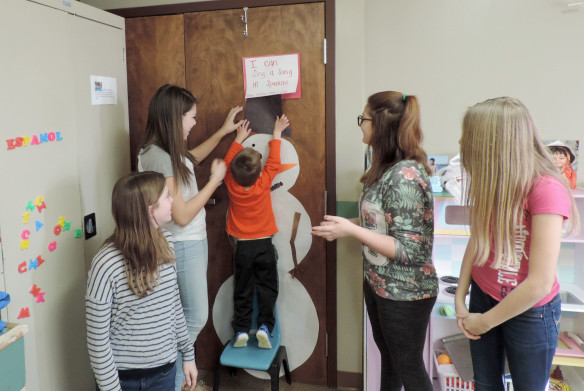 Camp Ernst Middle School students, from left, Emily Chaney, Sarah Willman, Leinda McNabb and Alyssa Land teach daycare students how to sing “Frosty the Snowman” in Spanish. Photo by Paige Holmes