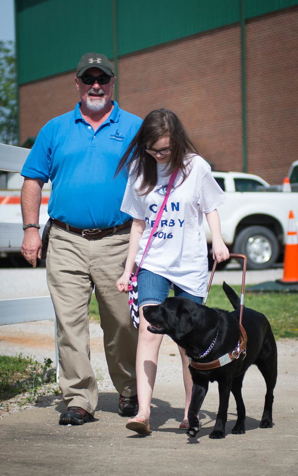 Haleigh Kemble, an 8th grader at Warren East Middle School, walks with John Dettloff and Daisy, the leader dog, during a leader dog demonstration at the Eye Can Derby. Photo by Bobby Ellis, April 29, 2016