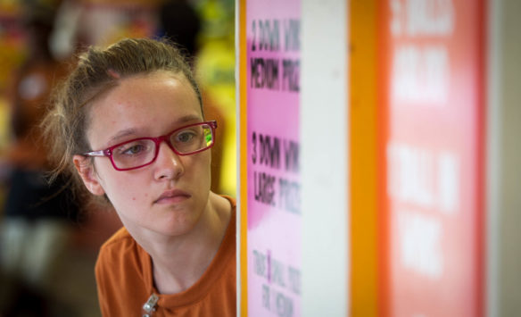 Kentucky School for the Blind junior Destiny Gregory reads a sign stating the rules of a game she is manning at Kentucky Kingdom. Photo by Bobby Ellis, June 24, 2016