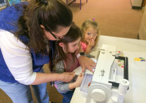 Geri Willis helps a Hager Elementary student sew a quilt square as part of a math-based quilting project. Photo by Kerri Keener