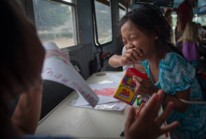 Thwey Kaw Paw Wah laughs with a friend while coloring on the Exploration Station bus. Six Daviess County elementary schools used the bus this summer to reach students who live in areas that typically experience the greatest summer slide. Photo by Bobby Ellis, July 18, 2016