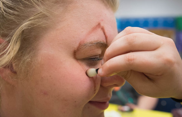 Amber Evans has makeup applied around her eyes to outline where the latex "skin" will be placed, the students travel to the Dent Haunted School House in Cincinnati, Ohio to learn proper makeup technique. Photo by Bobby Ellis, Oct. 14, 2016