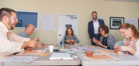 Kyle Lee, standing, looks on as educators (from left) Duwayne Dale of Daviess County, David Fonda of Montgomery County, Gena Maley of Murray Independent, Jane Dewey of Danville Independent, and Rachael Burriss of Boone County create pinch pots during a two-day conference for regional arts specialists held by the City of Berea/Tourism. Lee is coordinator of the visual and performing arts for the Kentucky Department of Education. Photo submitted