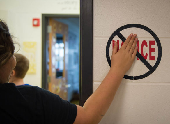 A Robertson County School student slaps a "No Novice" sign on as he leaves a classroom. The district started the practice as a way to motivate students. Last school year, no students performed a the novice level in 8th-grade social studies or 3rd-grade math. Photo by Bobby Ellis, Dec. 13, 2016