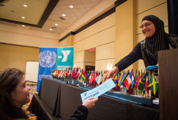 Nora Al-Shammari, a junior at the J. Graham Brown School (Jefferson County), hands out voting cards to students during the General Assembly at KUNA. Photo by Bobby Ellis, March 13, 2017