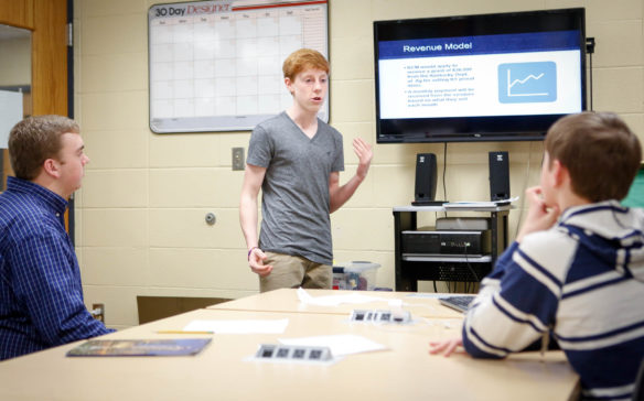 Ben Brown, standing, a student at Shelby County High School, practices his portion of a presentation for the Lieutenant Governor's Entrepreneurship Challenge with teammates Noah Gartland and Lunden Bryson. The three students, along with Paige Donovan, pitched the Kentucky Change Market on April 12 in one of five regional competitions. Photo by Mike Marsee, March 21, 2017