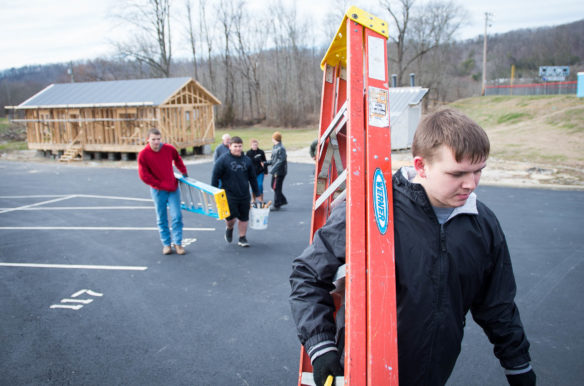 Casey County High School sophomore Chris Propes carries a ladder back to the classroom after working on a tiny house the class is building in the high school's parking lot.