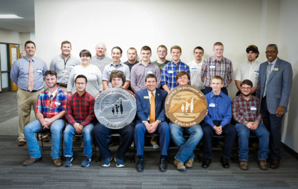 Students from Breckinridge County Area Technology Center present Kentucky Department of Education logos made of wood and aluminum to the Kentucky Board of Education at its meeting in Frankfort on April 12. Pictured, from left, are (seated) Luke Mattingly, Zane Denner, Hunter Robinson, Commissioner of Education Stephen Pruitt, Clayton Thompson, Coy Mattingly, Michael Nash, (standing) principal Jonathan Bennett, carpentry instructor Will Farmer, Ebonee East, CNC instructor Dean Monarch, Dalton Shepard, Jonathan Embry, Branden Kiper, Nathan Patterson, Wyatt Lucas, Austin Norton, Nathan Douglas, Nicholas Stinson and Kentucky Board of Education Chairman William Twyman. Photo by Mike Marsee, April 12, 2017