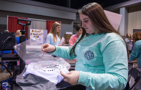 Kallie Shartzer, a senior at Breckinridge County High School, uses a heat press to transfer vinyl onto a T-shirt. The Breckinridge County High School STLP team sold custom T-shirts at the championship as part of their project and to raise money.