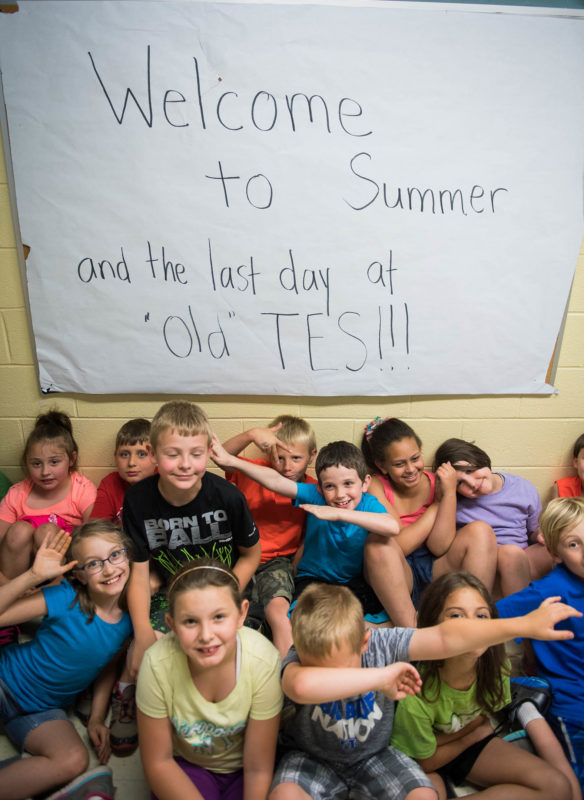 Second graders at Taylorsville Elementary sit in front of a sign welcoming summer and saying goodbye to the Taylorsville Elementary building. Photo by Bobby Ellis, May 23, 2017