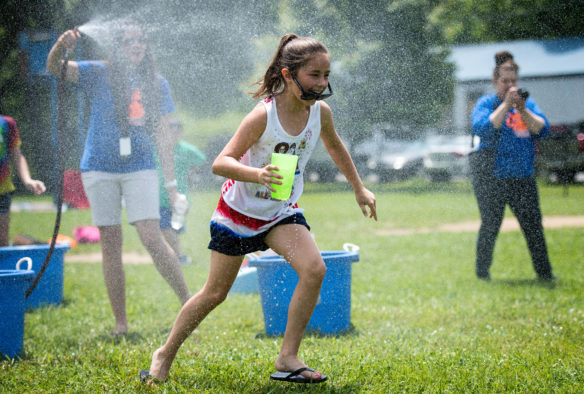Ava Raque runs through a spray of water while playing a game of "leaking cups" during the field day at Taylorsville Elementary.