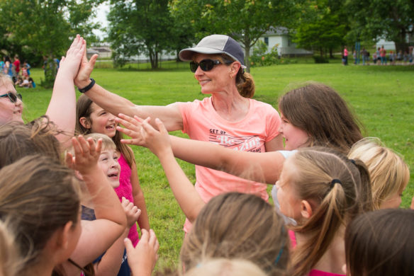 Sue Balter, an instructional assistant at Taylorsville Elementary, gets high fives from a group of students during the end of year field day. Photo by Bobby Ellis, May 23, 2017