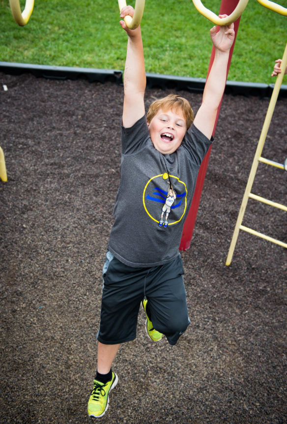 Kasey Coleman swings on the monkey bars while running through the obstacle course at the field day.