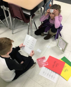 Students play heads up with a partner to define math vocabulary. A student holds up a vocabulary term on their forehead. Their partner is giving the definition and clues to help the student guess the term. Submitted photo by Emily Chandler