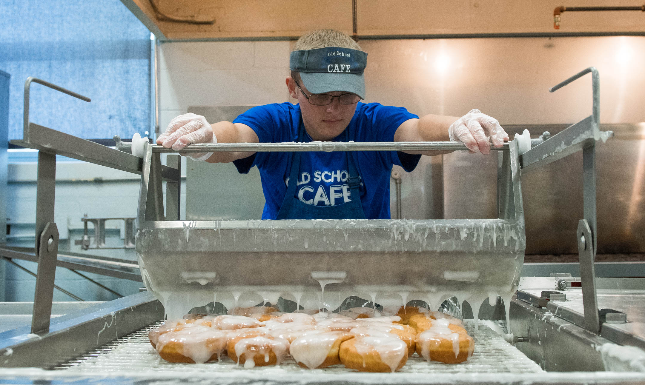 Metcalfe County High School student Taylor Brown glazes cinnamon roles while working at the Old School Cafe. Students can work one morning a week from 4 a.m. to 10 a.m. Photo by Bobby Ellis, May 24, 2017