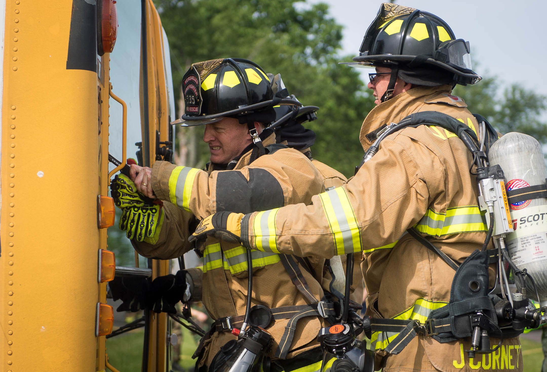 Woodford County firefighters use knives to cut out the windshield of a tipped school bus during a mass casualty simulation at the Bluegrass Railroad and Museum. Photo by Bobby Ellis, May 20, 2017