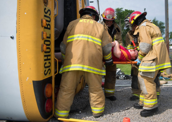 Woodford County firefighters carry out the actor portraying an injured bus driver, who received a simulated severe head wound during the crash.<br srcset=