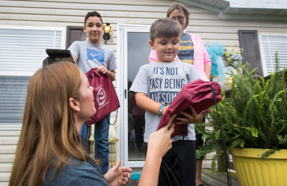 Tammy White, left, gives a backpack to Easton Ray, a kindergarten student at Providence Elementary (Webster County) during a home visit on the opening day of school in Webster County.  Photo by Bobby Ellis, Aug. 7, 2017