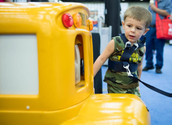 Jackson Curth, of Louisville, pets Buster the Bus while visiting the Kentucky Department of Education booth. Photo by Bobby Ellis. Aug. 24, 2017