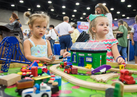 Ava Johnson, left, and Skylar Childs play with toy cars in the Kentucky Main Street area of the Kentucky State Fair.  Photo by Bobby Ellis, Aug. 24, 2017
