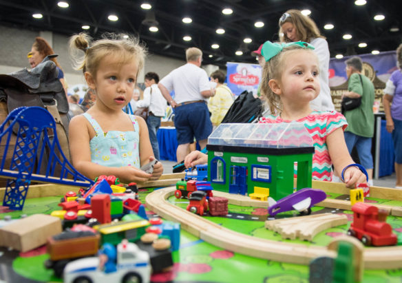 Ava Johnson, left, and Skylar Childs play with toy cars in the Kentucky Main Street area of the Kentucky State Fair. Photo by Bobby Ellis, Aug. 24, 2017